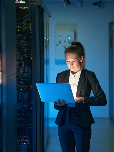 Woman using laptop by server