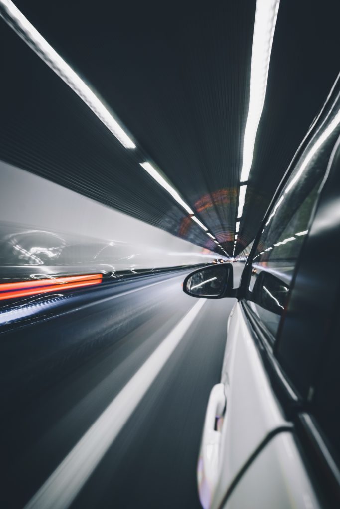 Car driving through a tunnel with speeding lights passing by.
